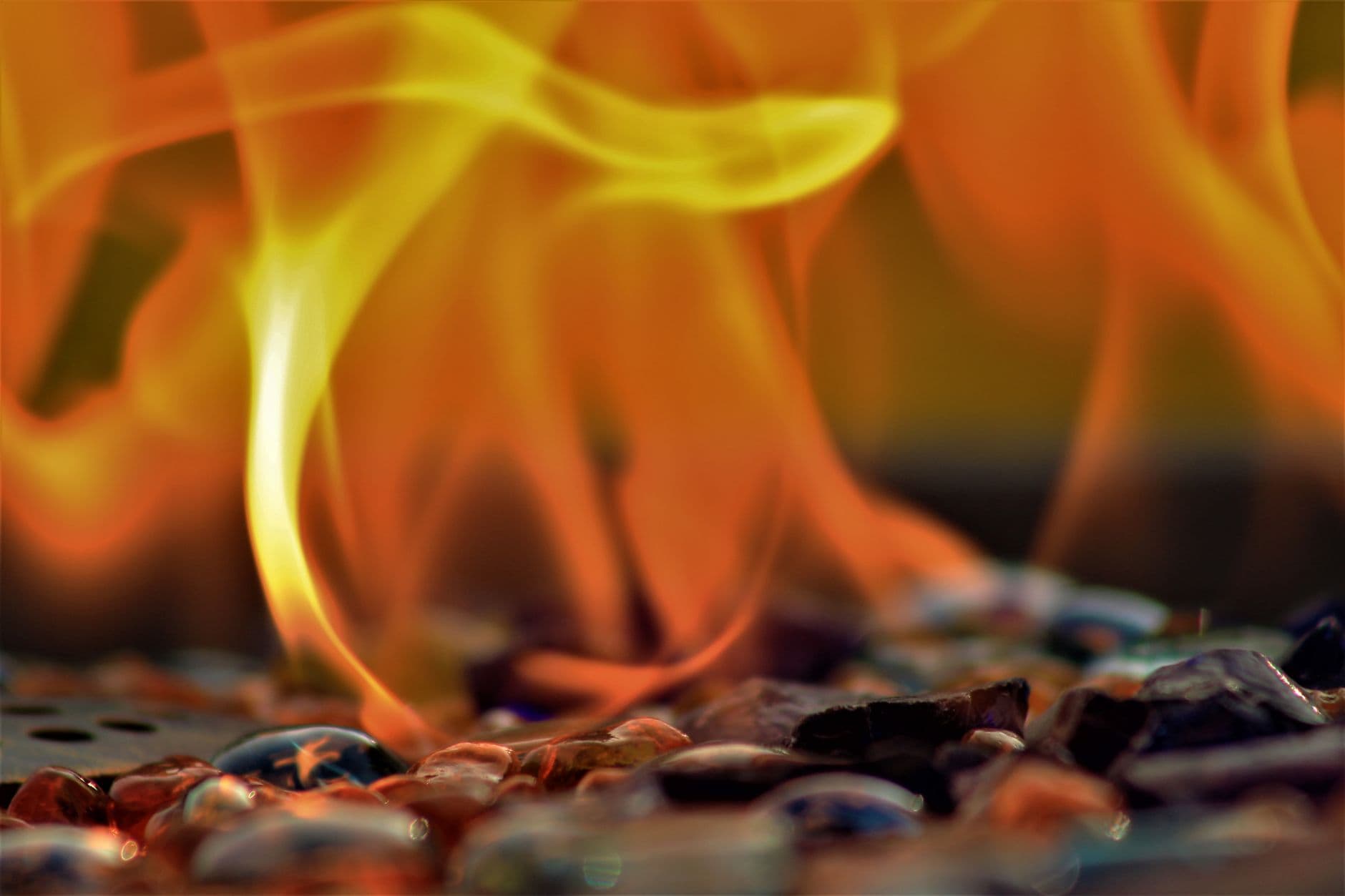 Close-up of vibrant flames flickering over colorful charred coals, capturing intense energy and heat.