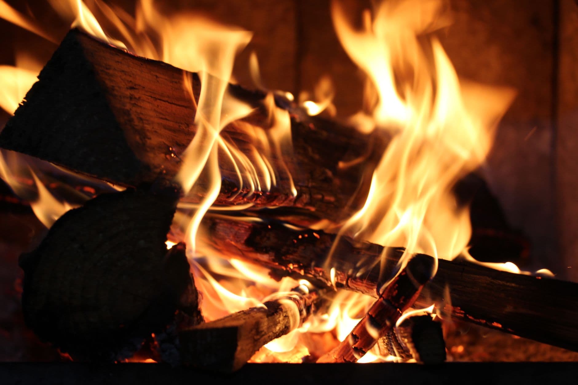 Captivating close-up shot of burning logs in a fireplace with warm flickering flames.